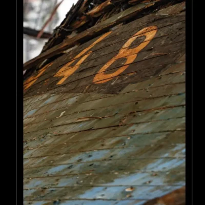 Photo artistique d’un bateau abandonné avec numéro 448. Bois patiné, peinture écaillée, ambiance maritime nostalgique. Idéal pour blog sur patrimoine portuaire, fiches techniques d’épaves marines, design vintage ou inspiration artistique. Mots-clés : bateau abandonné, numéro 448, bois vieilli, épave maritime, photographie artistique, patrimoine marin, Ordigraph.