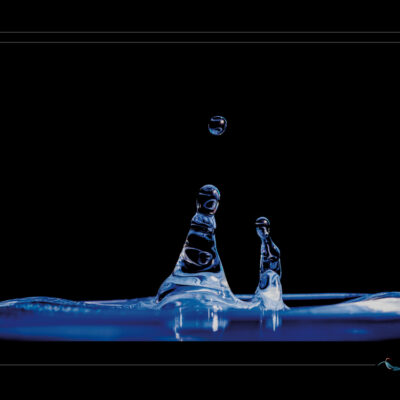 Découvrez L’éveil des colonnes, une photographie artistique de gouttes d’eau en suspension, illustrant la beauté de la fluidité et de l’impact. Cette image de haute précision révèle les secrets de la tension superficielle et du mouvement liquide. Idéale pour les passionnés de physique, d’art visuel et de photographie scientifique. Série Silence liquide — fluides en apesanteur, lumière bleue, fond noir, impact et rebond. Ordigraph