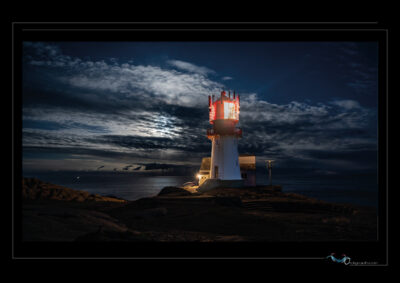 Photo nocturne du phare de Lindesnes en Norvège, paysage côtier avec rochers, ciel nuageux, lumière de phare, ambiance dramatique et mer calme. Image scandinave haute définition, architecture maritime, solitude nordique et atmosphère contemplative. Idéal pour blog de voyage, site photo, inspiration nordique et récits visuels. Ordigraph