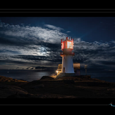 Photo nocturne du phare de Lindesnes en Norvège, paysage côtier avec rochers, ciel nuageux, lumière de phare, ambiance dramatique et mer calme. Image scandinave haute définition, architecture maritime, solitude nordique et atmosphère contemplative. Idéal pour blog de voyage, site photo, inspiration nordique et récits visuels. Ordigraph