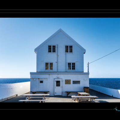 Photo du bâtiment de Kinn en Norvège, architecture blanche en bord de mer, lieu de passage, horizon bleu, ambiance minimaliste et contemplative. Image scandinave haute définition, idéale pour blog de voyage, site photo et récits poétiques. Ordigraph