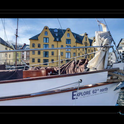 Photo du port d’Ålesund avec voilier amarré, hôtel Brosundet, façades colorées, eau calme et lumière nordique. Image haute définition, ambiance maritime et urbaine, idéale pour blog de voyage, site photo, inspiration scandinave et récits contemplatifs. Ordigraph