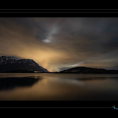 Photo de coucher de soleil sur montagnes, lac calme, lumière chaude, silhouettes sombres et reflets. Image haute définition, ambiance crépusculaire et contemplative, idéale pour blog de voyage, site photo, inspiration scandinave et récits visuels. Ordigraph